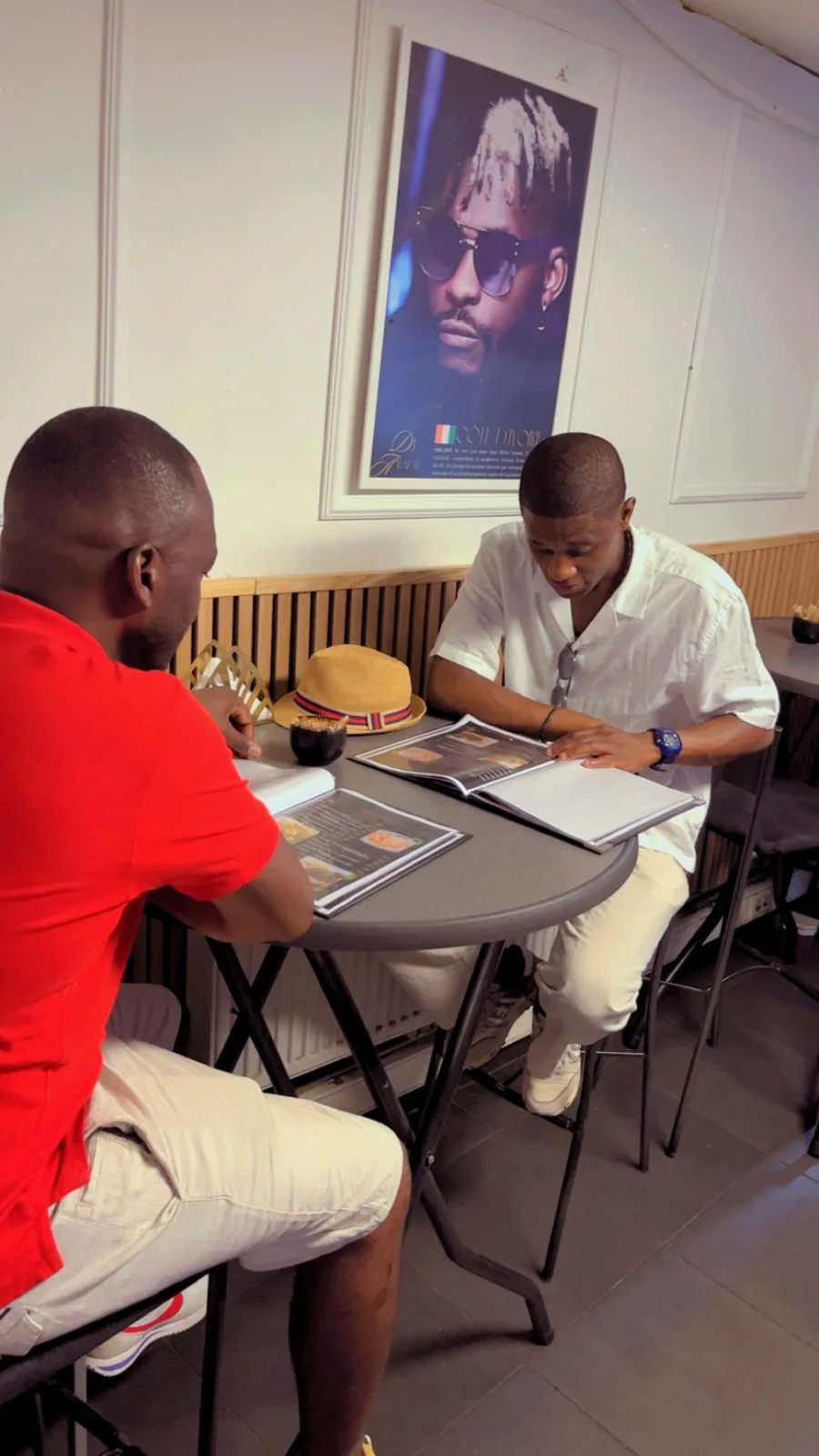 Deux clients consultent la carte à une table haute de la salle