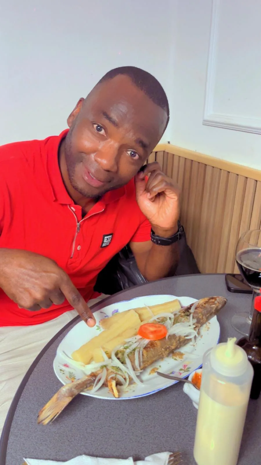 Client devant son assiette de poisson braisé et bâtons de manioc