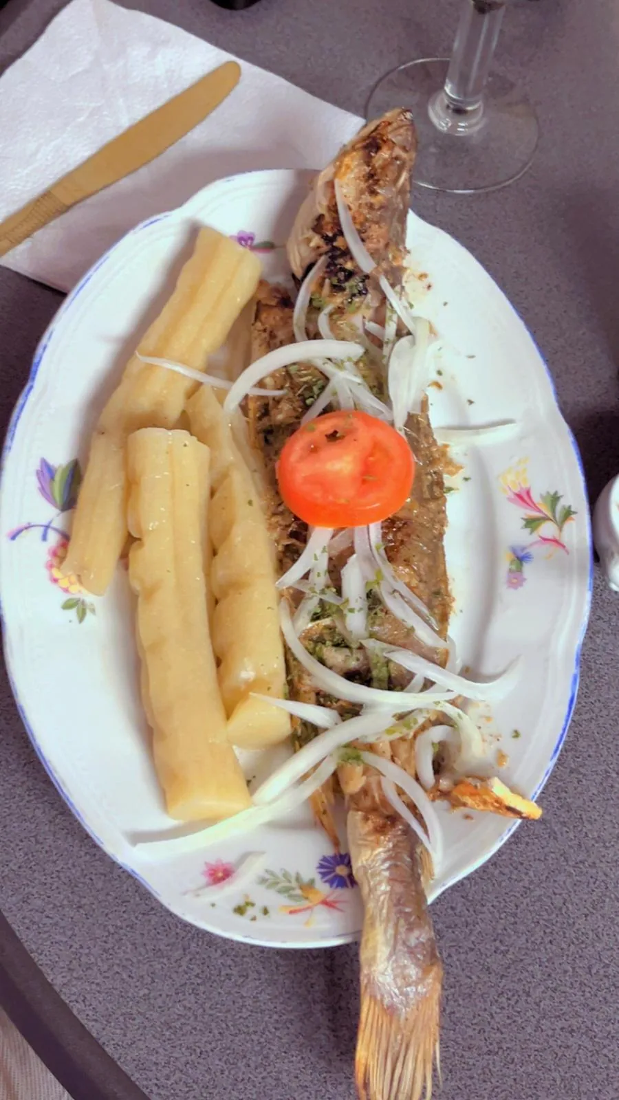 Poisson braisé entier, bâtons de manioc, oignons et tomate