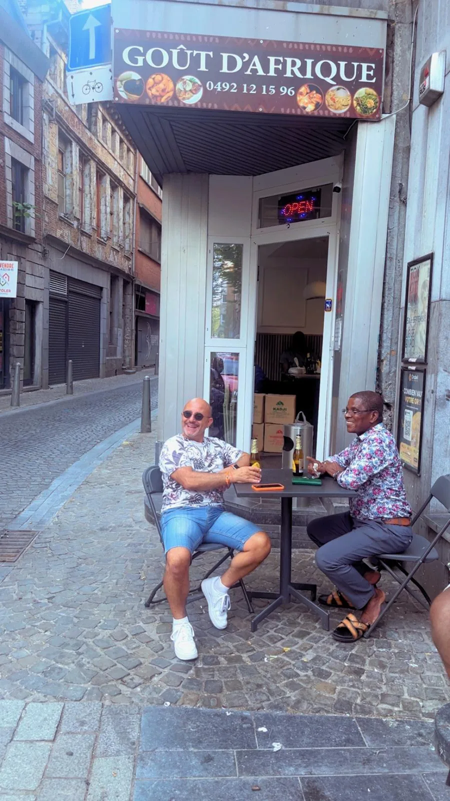 Deux clients en terrasse devant l’enseigne du restaurant